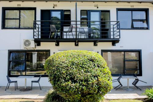 a house with a balcony and a bush in front of it at Vetho 1 Apartments OR Tambo Airport in Johannesburg