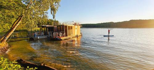 a boat on a lake with a house on it at Domek pływający HouseBoat 4U in Ruciane-Nida