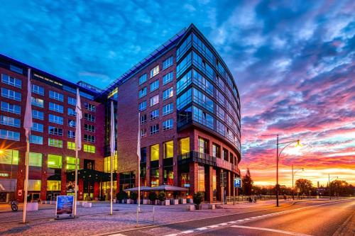 a building on a city street with a sunset at ScanHotels City in Rostock
