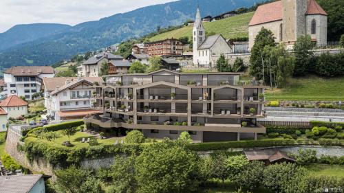 a large building on a hill next to a town at Egger Apartments & Suites in Villandro