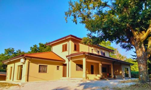 a yellow house with a tree in front of it at Alberi Maestri Eco Retreat in Satriano di Lucania