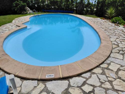 a large blue swimming pool with a stone pathway around it at Quinta Do Mar in Colares