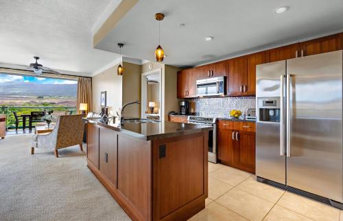 a kitchen with wooden cabinets and a stainless steel refrigerator at Honua Kai Resort And Spa By Maui Resort Rentals in Lahaina