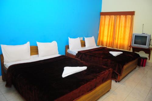 twee bedden in een hotelkamer met een tv bij Hotel Zaraa in Ooty