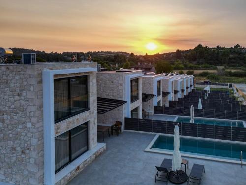 a building with a pool and a sunset in the background at The Olive Path in Kalandra