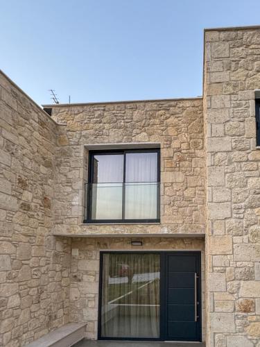 a stone house with a black door and windows at The Olive Path in Kalandra