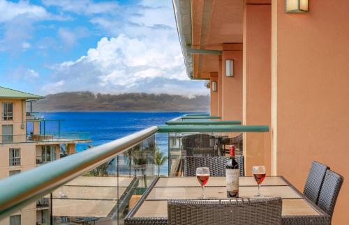 a balcony with a table and two glasses of wine at Honua Kai Resort And Spa By Maui Resort Rentals in Lahaina