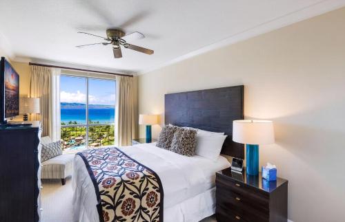 a bedroom with a bed and a window with the ocean at Honua Kai Resort And Spa By Maui Resort Rentals in Lahaina