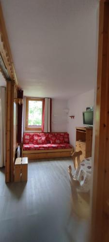 a living room with a red couch and a window at Studio divisible Montchavin draps serviettes torchons non fournis Ménage à faire in La Plagne Tarentaise