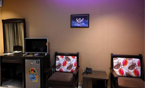 a living room with two chairs and a tv at BARADA Hotel- فندق بردى in Qaryat al Bulush
