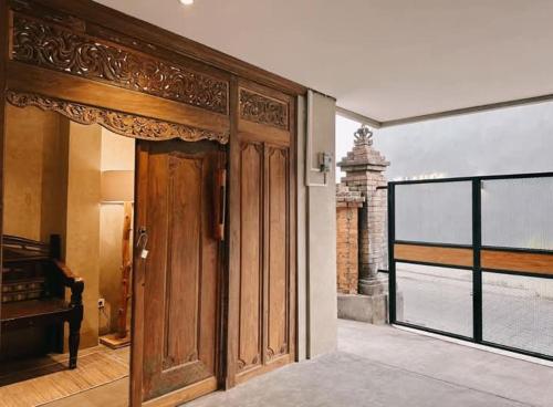 una entrada a una casa con una puerta de madera en Victory Beloved House Sanur Private Rooms Villa Bali, en Sanur