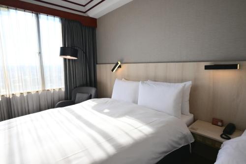 a hotel room with a large white bed and a window at T Hotel in Taichung