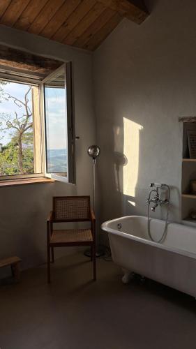 Un baño con bañera, silla y ventana. en Casa Cunicchio, en SantʼElpidio a Mare