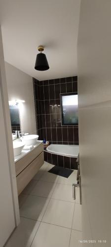 a bathroom with two sinks and a bath tub and a tub at La Velaysienne 5 étoiles piscine,sauna, jacuzzi in Le Monteil