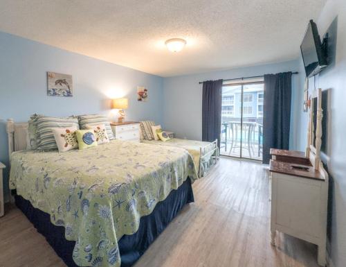 a bedroom with a bed and a television and a window at Sea Oats B106 by ALBVR - Pet Friendly - Great renovation and tons of space in this condo - Outdoor Pools, Pier, and Dedicated Beach Access in Gulf Shores