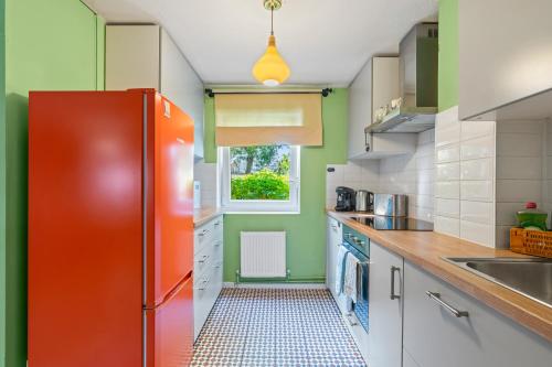 an orange refrigerator in a kitchen with a window at Summer Deals up to 20 Percent OFF! Cosy Central London Family Stay Near Top Attractions - London Bridge & Shard - 3 Nearby Stations & Parking - WiFi & Games! in London