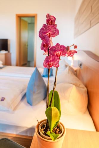 a flower in a pot on a table next to a bed at Landhotel Tannenhof in Spiegelau