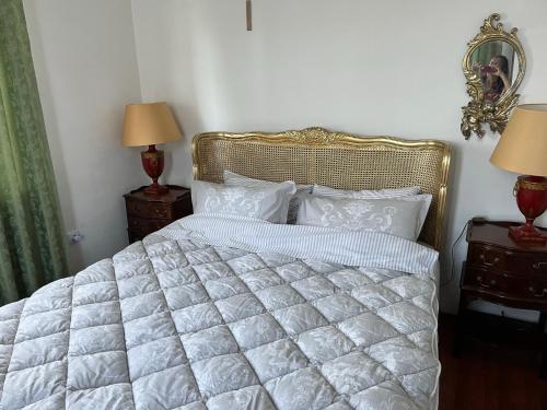 a bedroom with a white bed with two lamps and a mirror at Villa Royal in Cetinje