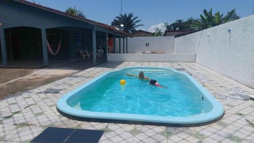 a child in a swimming pool with a ball at Casa COP 30 BELÉM-Mosqueiro in Belém