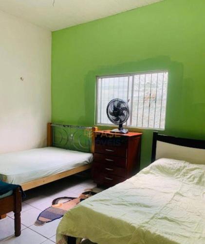 a bedroom with green walls and two beds and a fan at Casa COP 30 BELÉM-Mosqueiro in Belém