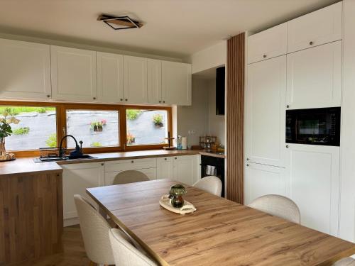Una cocina con una mesa de madera y gabinetes blancos. en Villa Koscielisko, en Kościelisko