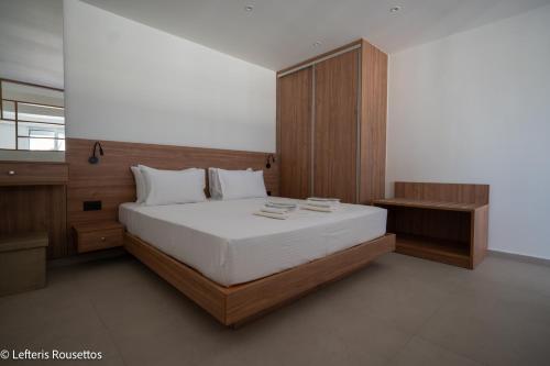 Un dormitorio con una cama grande y un armario de madera. en Rodos Suites on the Park, en Rodas