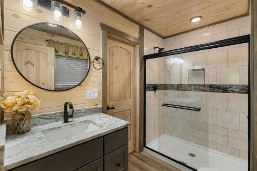 Un baño con ducha, lavabo y espejo. en Views Forever by American Patriot Getaways, en Chalet Village