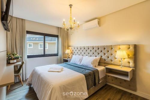 Apto Encantador c/ lareira em Gramado STA0305 في غرامادو: غرفة نوم بها سرير كبير وثريا