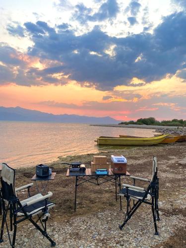 a picnic table and chairs on the beach with a boat at 4x4 car camping in Theth