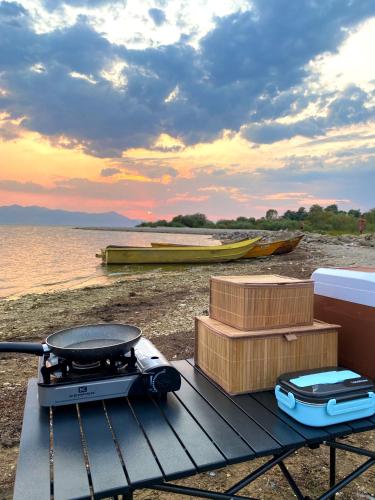 a grill and boxes on a table next to the water at 4x4 car camping in Theth