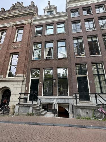 a large brick building with windows on a street at Herengracht 204 Souterrain Studio Apt without kitchen in Amsterdam