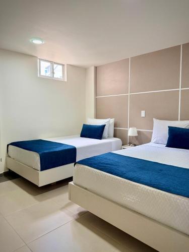 a bedroom with two beds with blue sheets at Hotel Boutique Paralela Real. in Manizales