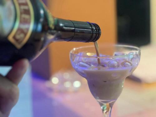 にあるHotel Rubyのワイングラスにワインのボトルを注いでいる人