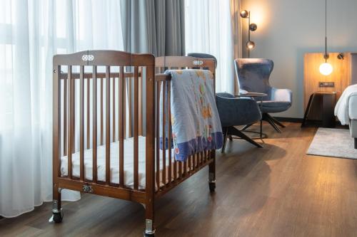 a crib in a room with a bed and a chair at ScanHotels City in Rostock