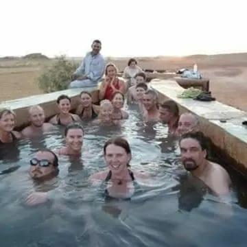 a group of people in a pool of water at White & Black Desert Camping in Az Zabū