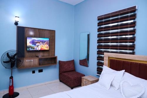 a bedroom with a bed and a tv and a chair at Ay crib in Kaduna