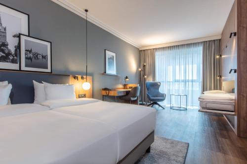 a bedroom with a large white bed and a desk at ScanHotels City in Rostock