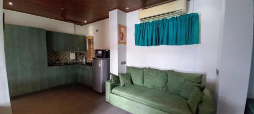 a living room with a green couch and a kitchen at Pearl Spot in Alwaye