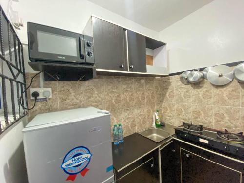 a small kitchen with a refrigerator and a microwave at Studio apartment in Lagos
