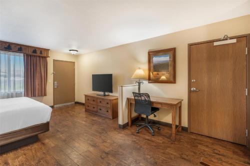 a hotel room with a bed and a desk with a computer at Best Western Plus Kelly Inn & Suites in Billings