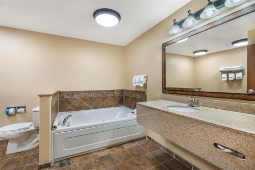 a bathroom with a tub and a toilet and a sink at Best Western Plus Kelly Inn & Suites in Billings