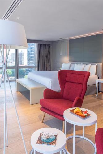 a hotel room with a bed and a red chair at NH Collection Mexico City Reforma in Mexico City