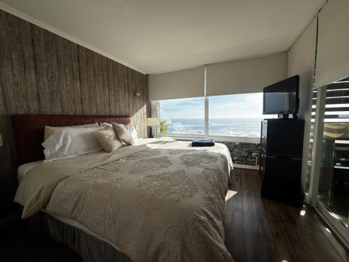 a bedroom with a large bed and a large window at Reñaca Cochoa departamento frente al mar in Vina del Mar