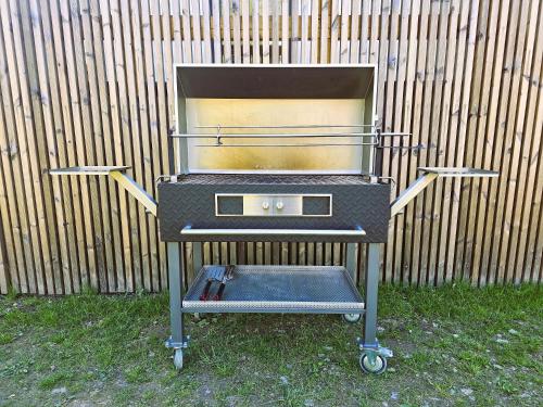 a grill sitting in the grass in front of a fence at Apartmán v tichu in Teplice nad Metují