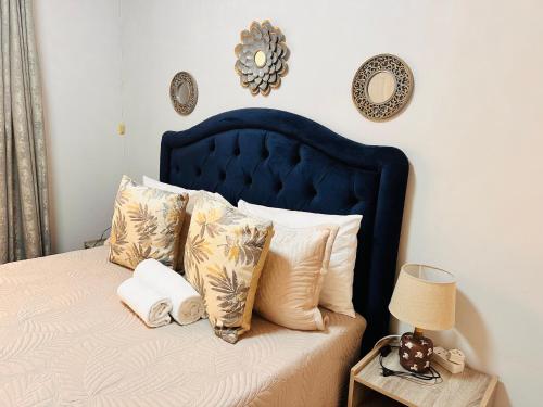 a bed with a blue headboard and pillows on it at Home For You in Gaborone