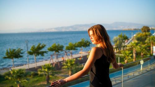 a woman standing on a balcony looking at the ocean at RUKA Hotel in Narlıdere