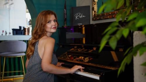 a woman in a dress playing a piano at RUKA Hotel in Narlıdere