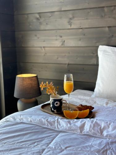 a tray of food and a glass of wine on a bed at Black Villa, Aurora View Bath & Sauna, Private Design Villa in Lapland in Kolari