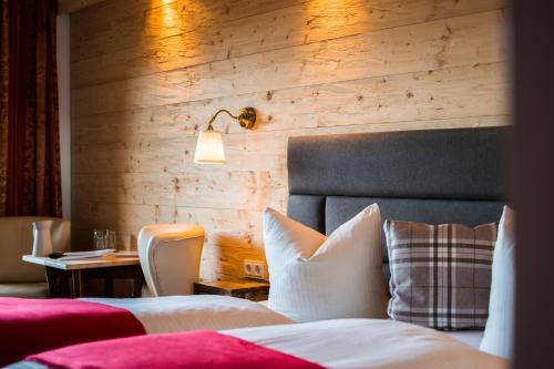 a bedroom with a bed and a table with a lamp at Hotel Berghof in Nesselwängle