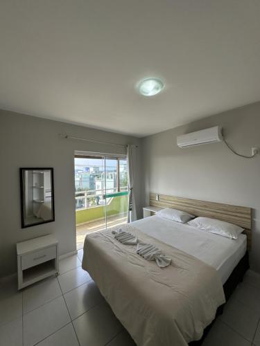 a bedroom with a large bed and a large window at Pousada Brisa do Mar in Bombinhas